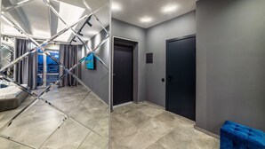 Un intérieur moderne avec un sol carrelé, un escalier doté de rampes en métal et un banc recouvert d’un tissu bleu.