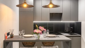 Une cuisine moderne dotée d’un îlot central, de luminaires suspendus et d’un vase rempli de fleurs.