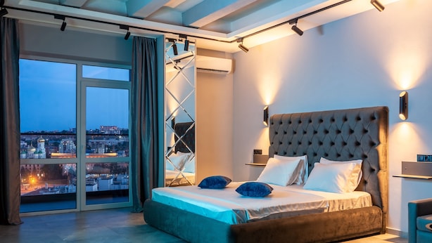 Une chambre moderne avec un grand lit, une vue sur la ville et une porte coulissante donnant sur un espace extérieur.