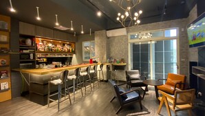 Zona de bar moderna con mostrador, taburetes y un área de estar con sillas y una mesa.
