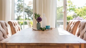 Un tavolo da pranzo con un vaso di fiori, una bottiglia e una tazza, posto tra due poltrone imbottite.