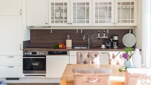 Una cucina moderna con mobili bianchi, un piano di lavoro in legno e una zona pranzo con tavolo e sedie.