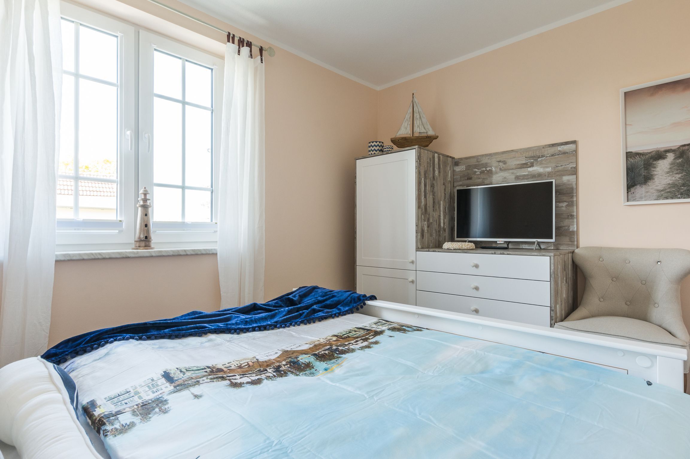 A bedroom with a bed, a TV, a wardrobe, and a chair.
