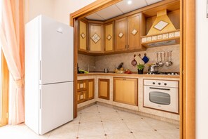 Una cocina con armarios de madera, un refrigerador blanco, una estufa y varios utensilios de cocina.