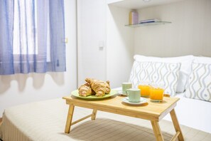 A bed with a white and patterned pillow, a bedside table with croissants, a green plate, two mugs, and two glasses of orange juice. - Spacious 3 bedrooms apartment in Sorrento OldTown (Sorrento)
