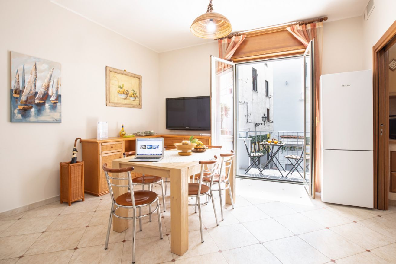 Eine Küche mit Essbereich, einem Fernseher und einem Balkon mit Tisch und Stühlen.