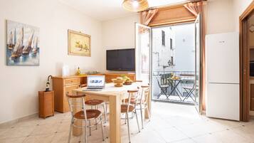 Eine Küche mit Essbereich, einem Fernseher und einem Balkon mit Tisch und Stühlen.