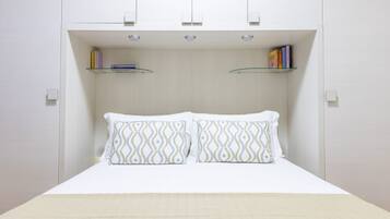 A bedroom with a bed, two pillows, and two shelves with books.