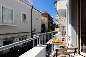 A narrow street with buildings on either side, a balcony with a table set for breakfast, and a shop named "Capri Breeze".