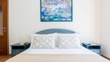 Une chambre à coucher avec un lit, deux tables de chevet, un tableau et une porte.