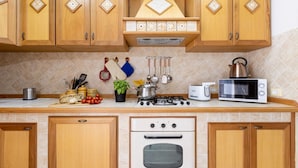 A kitchen with wooden cabinets, a gas stove, a microwave, and various kitchen utensils.