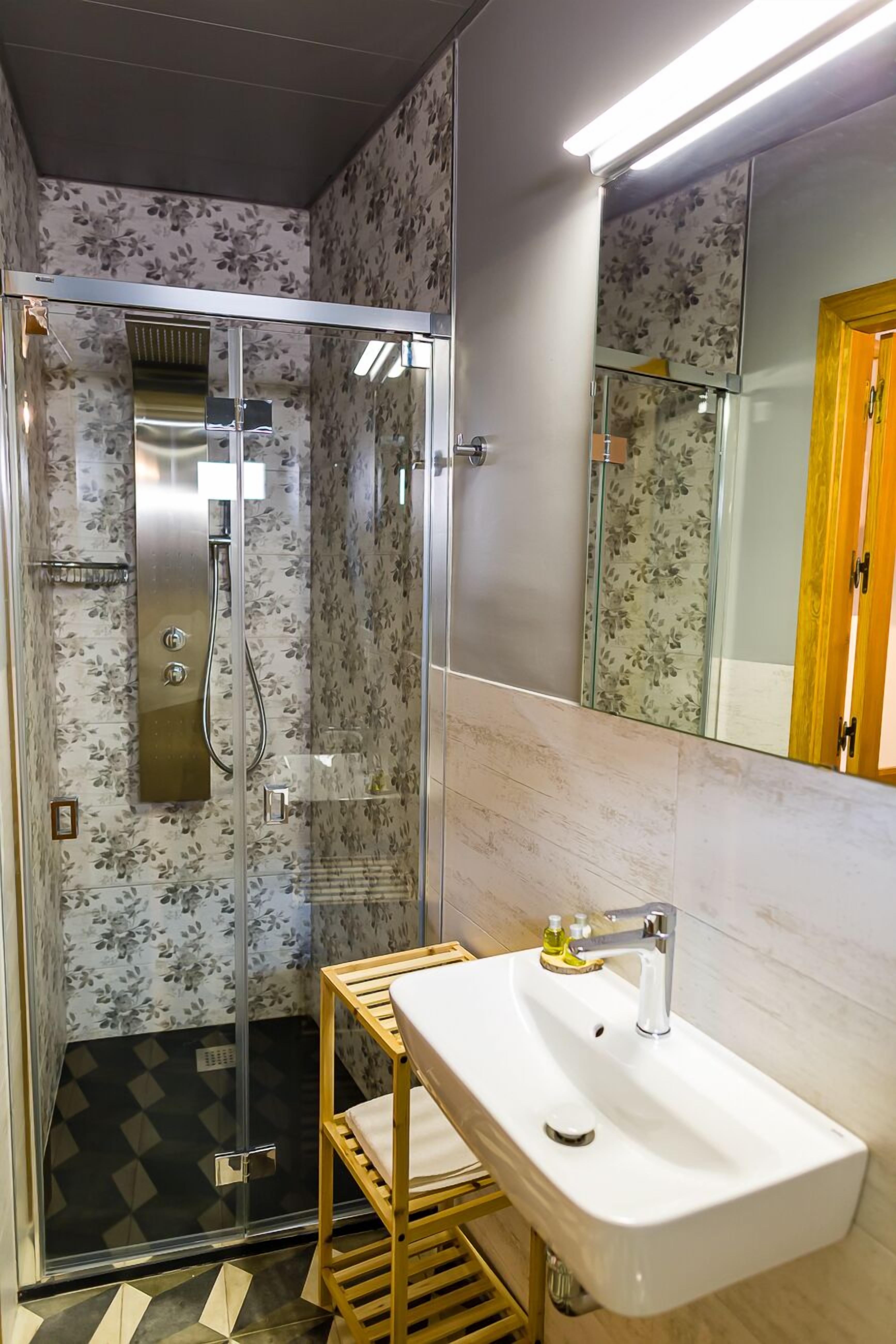 Une salle de bain avec une douche, un lavabo et un miroir.