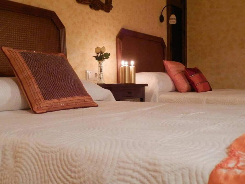 Una habitación de hotel con una cama grande, una mesita de noche con velas y un jarrón con flores.
