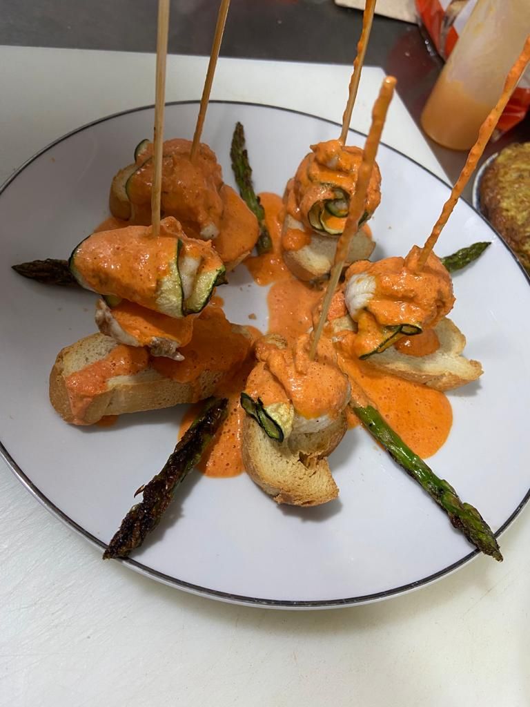 Un plato de comida con brochetas y espárragos.