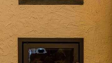 A fireplace with a television screen, a wall-mounted light fixture, and a ventilation vent.