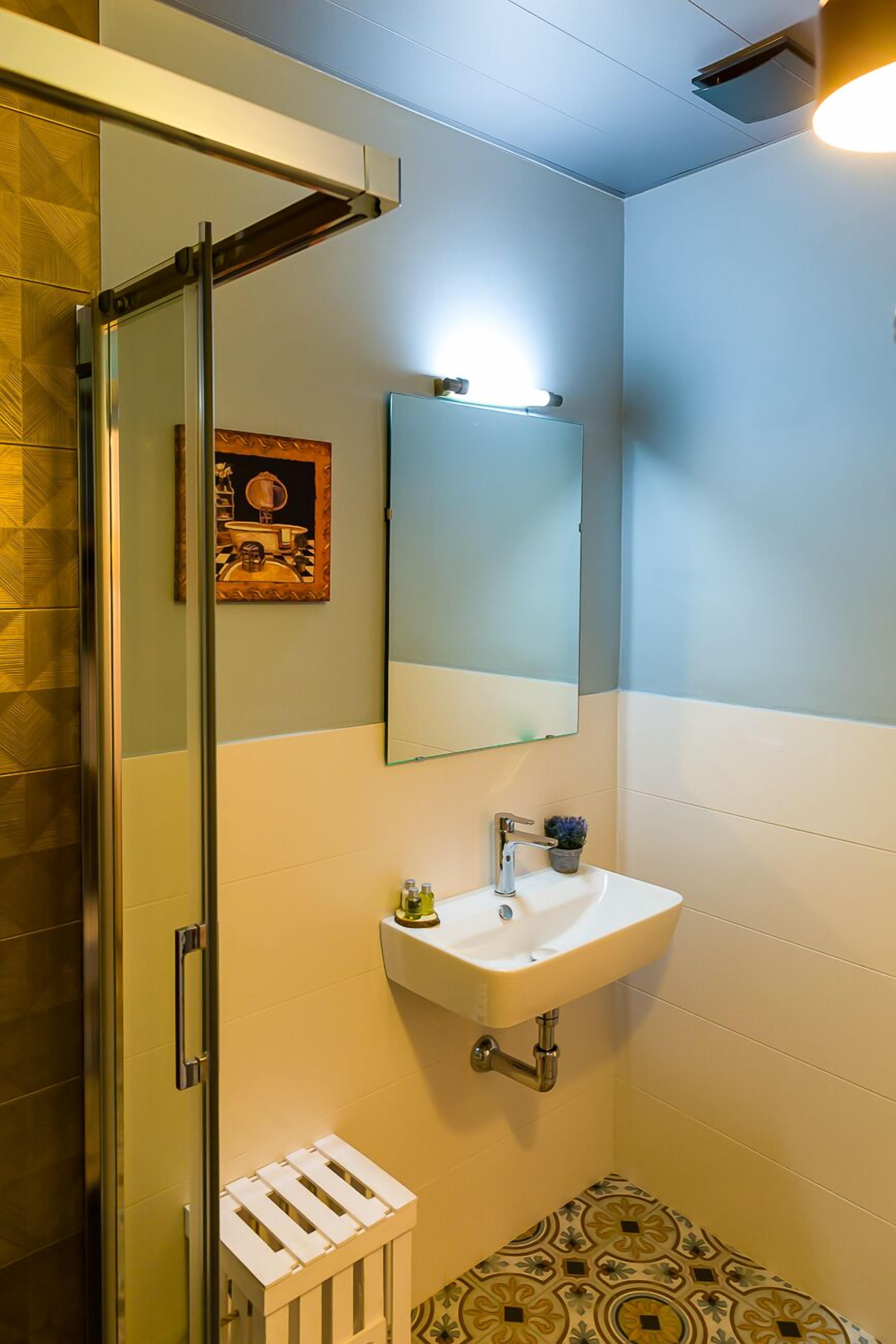 Ein Badezimmer mit Duschkabine aus Glas, einem weißen Waschbecken und einem Spiegel.