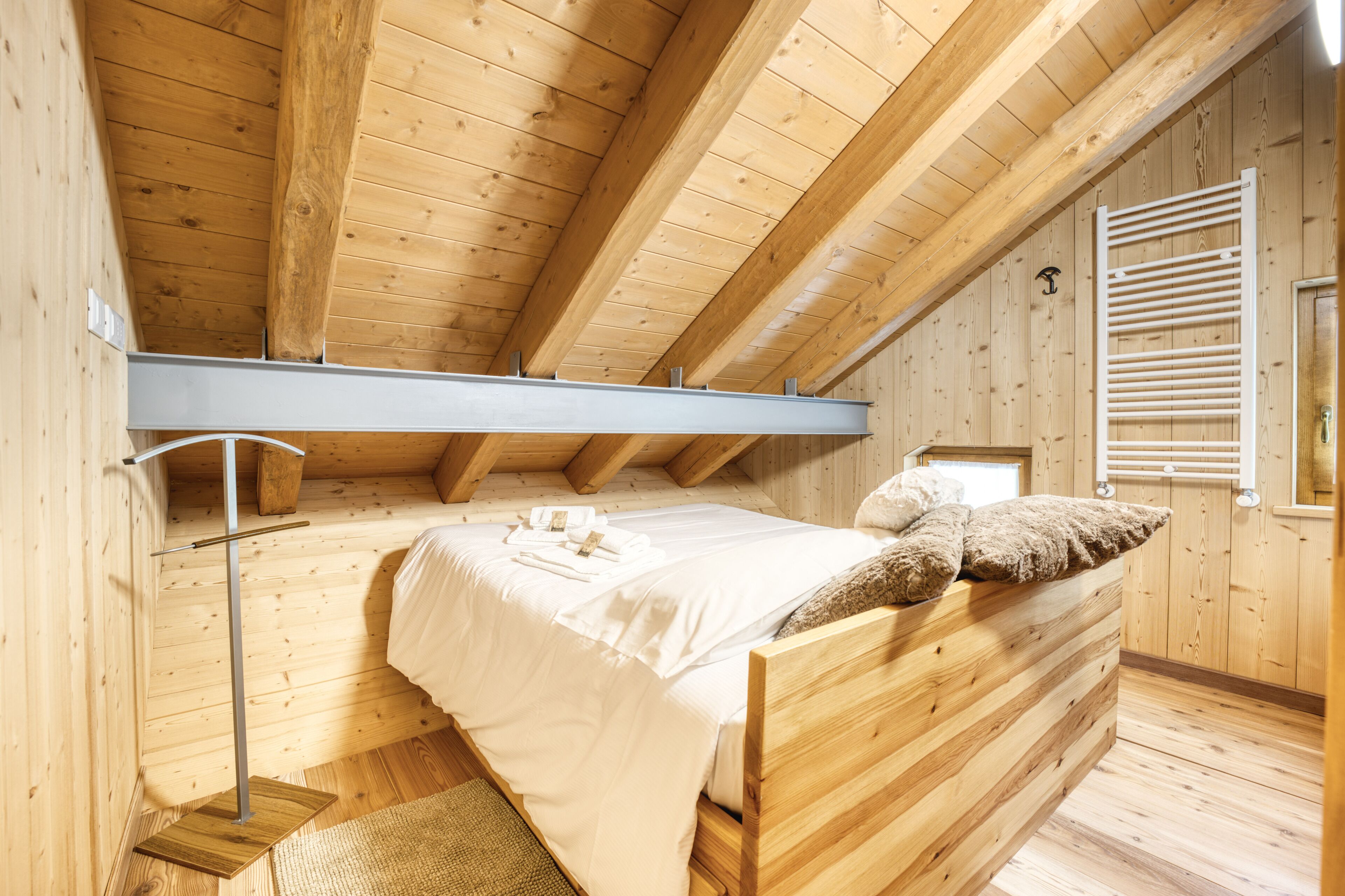 Een slaapkamer in een houten hutje, met een stapelbed, een metalen plank en een raam met luiken.