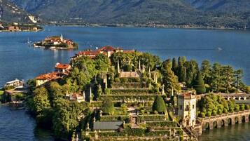 Eine historische Insel mit angelegten Terrassengärten, einer Brücke und einem Gewässer mit Bergen im Hintergrund.