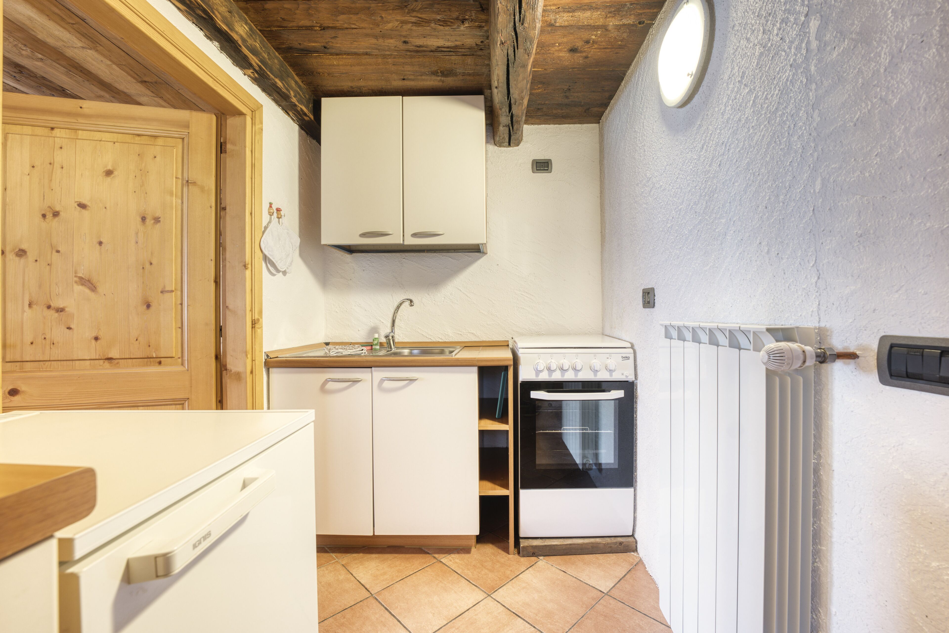 A compact kitchen with wooden cabinets, a white stove, and a tiled floor.