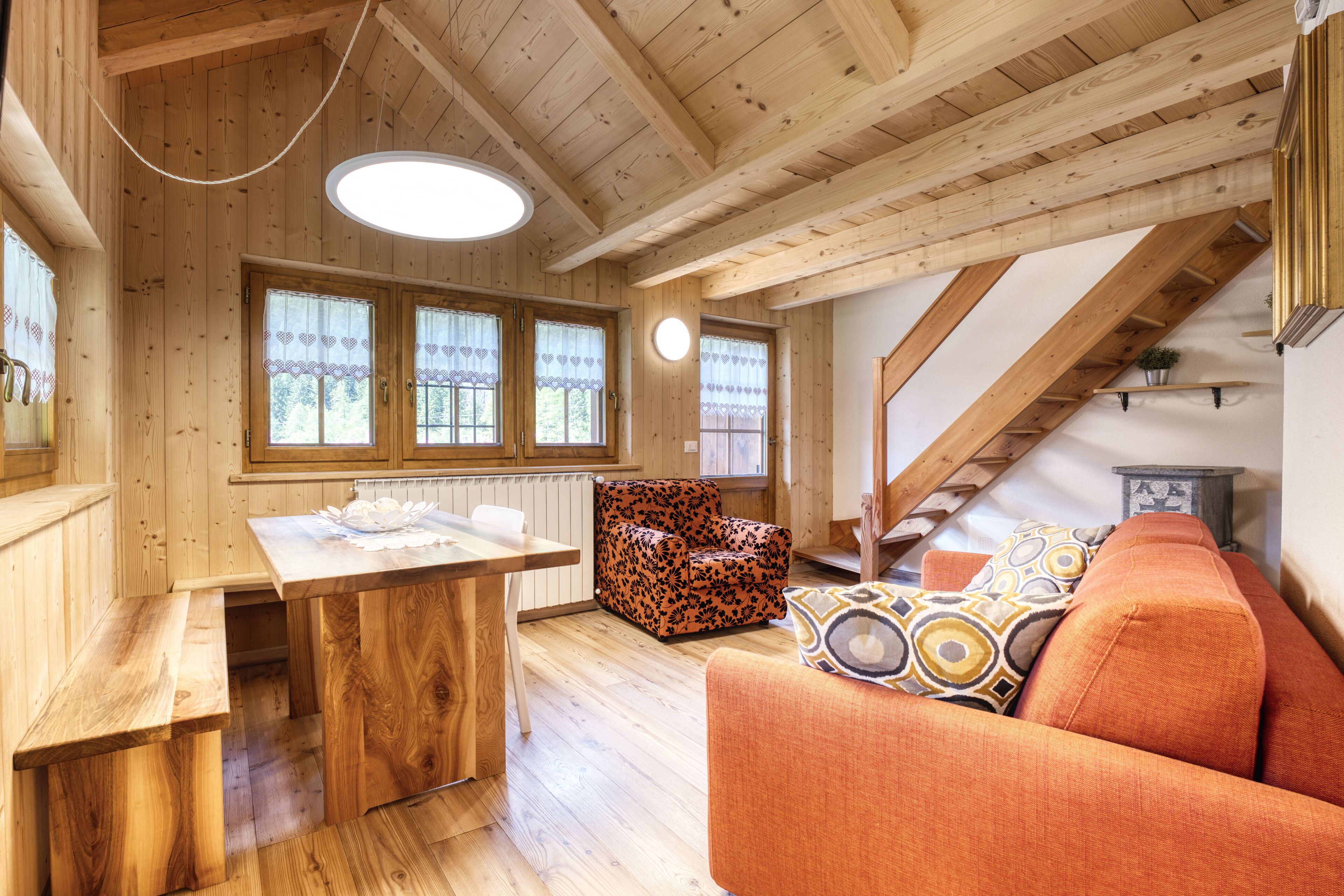 Un interior de madera con comedor, sofá y escalera.