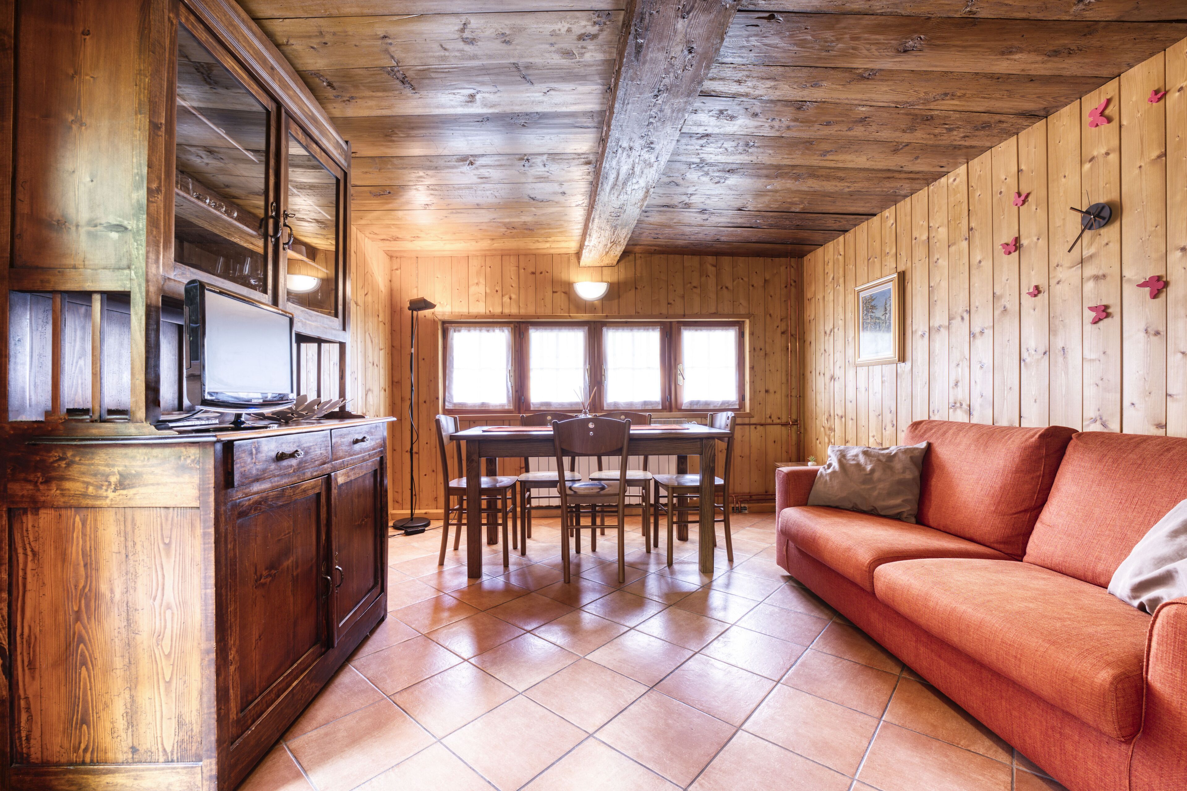 Ein Holzinnenraum mit Esstisch, Stühlen, einer Couch und einem Schrank.