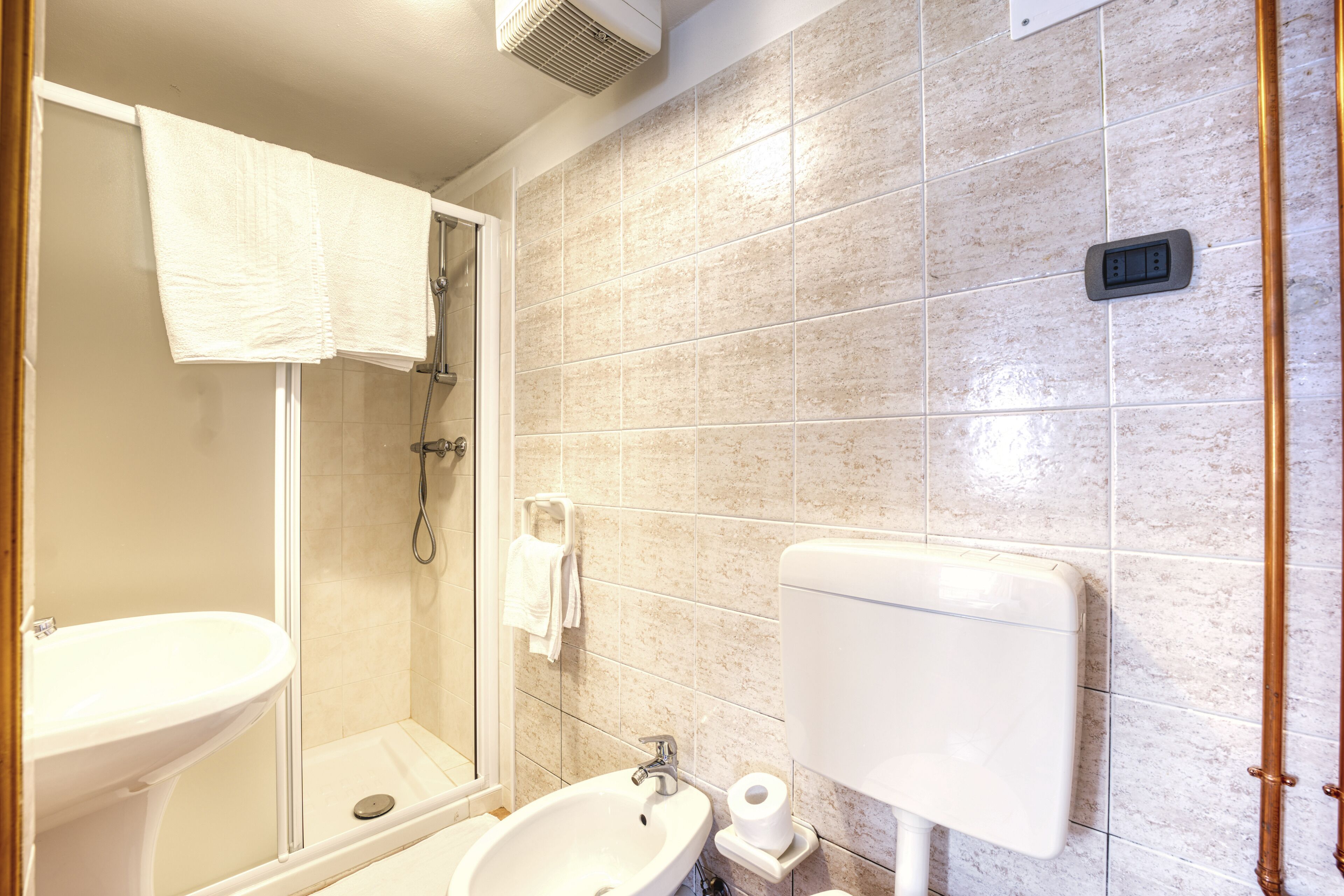 Un bagno con cabina doccia in vetro, lavandino e WC.