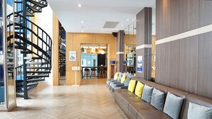 A modern hotel lobby with a spiral staircase, a seating area with cushions, and a wooden wall. - Kokotel Bangkok Dheva Thonglor (Bangkok)