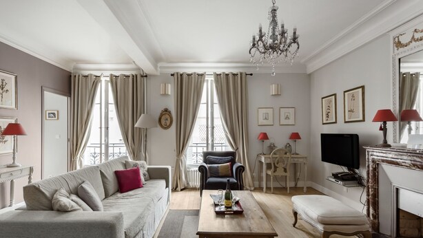 A living room with a sofa, ottoman, coffee table, and a fireplace. - Amazing modern apartment next to EiFFEL TOWER (Paris)