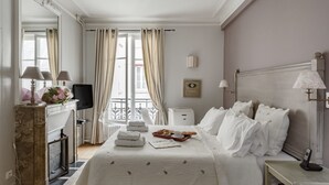 A hotel room with a bed, bedside table, lamp, and a view of the outside through a window. - Amazing modern apartment next to EiFFEL TOWER (Paris)