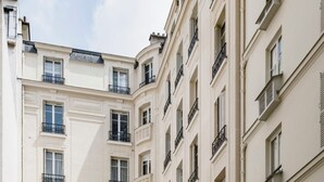 A multi-story residential building with balconies, a central entrance, and a courtyard. - Amazing modern apartment next to EiFFEL TOWER (Paris)