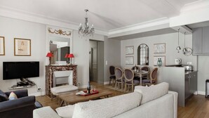 A modern living room with a sofa, TV, fireplace, dining area, and kitchen. - Amazing modern apartment next to EiFFEL TOWER (Paris)