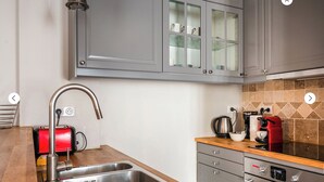 A modern kitchen with grey cabinets, a stainless steel sink, a red toaster, a coffee maker, and a built-in oven. - Amazing modern apartment next to EiFFEL TOWER (Paris)