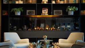 Uma área de estar moderna com lareira, assentos confortáveis e objetos decorativos nas prateleiras.