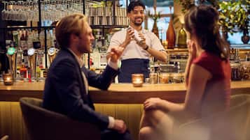 Un bar con un cantinero, un hombre sentado y una mujer.