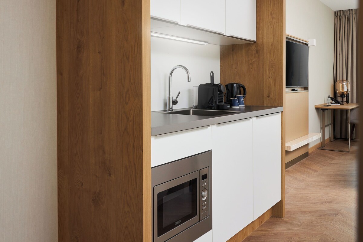 A modern kitchen with a built-in oven, a stainless steel sink, and a coffee maker.