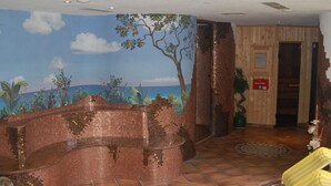 Un espace de détente avec un mur décoré de mosaïques, une porte en bois et des chaises à rayures jaunes.