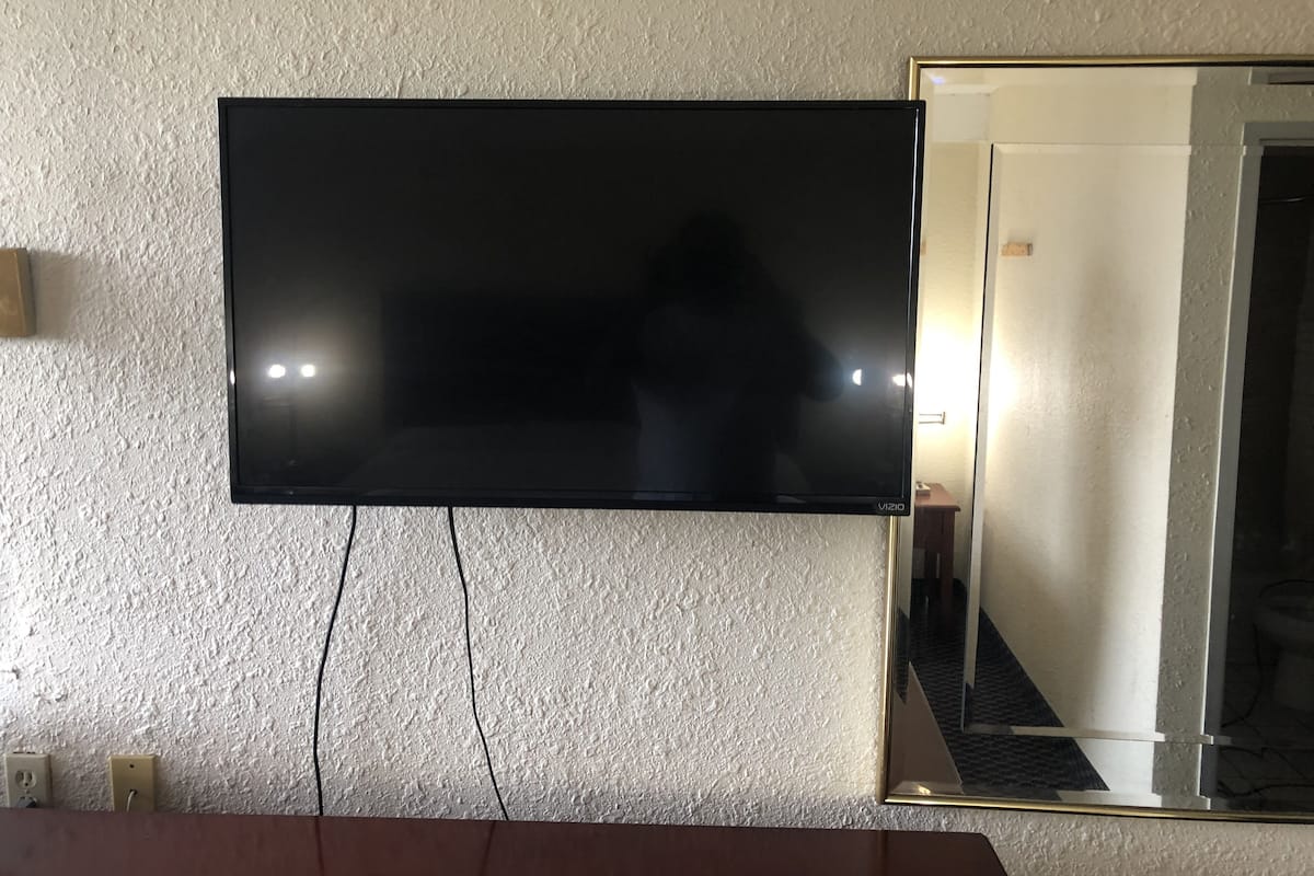 Un televisor de pantalla plana montado en una pared con textura y tomas de corriente visibles debajo.