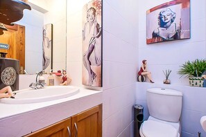 A modern bathroom with a large mirror, a sink, a toilet, and decorative artwork. - Vaal River YOLO Spaces – Vaal River Bush Lodge (Metsimaholo)