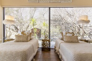 A room with two beds, a small table, and a potted plant. - Vaal River YOLO Spaces – Vaal River Bush Lodge (Metsimaholo)