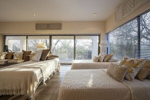 A bedroom with two beds, large windows, and a view of trees. - Vaal River YOLO Spaces – Vaal River Bush Lodge (Metsimaholo)