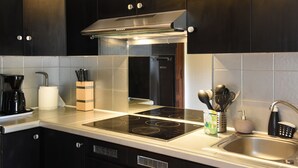 A modern kitchen with dark cabinets, a stainless steel sink, and a built-in stovetop. - Gite Nature et Détente 6/8p with private jacuzzi (Marions)