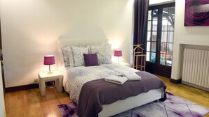 A bedroom with a bed, two bedside lamps, a window with curtains, and a radiator. - Gite Nature et Détente 6/8p with private jacuzzi (Marions)
