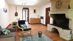A living room with a stone fireplace, a wooden cabinet, a dining table with chairs, and a couch. - Gite Nature et Détente 6/8p with private jacuzzi (Marions)