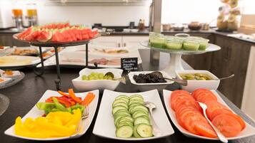 Ein Buffet mit verschiedenen Speisen, darunter Wassermelone, Gurkenscheiben und Tomatenscheiben.