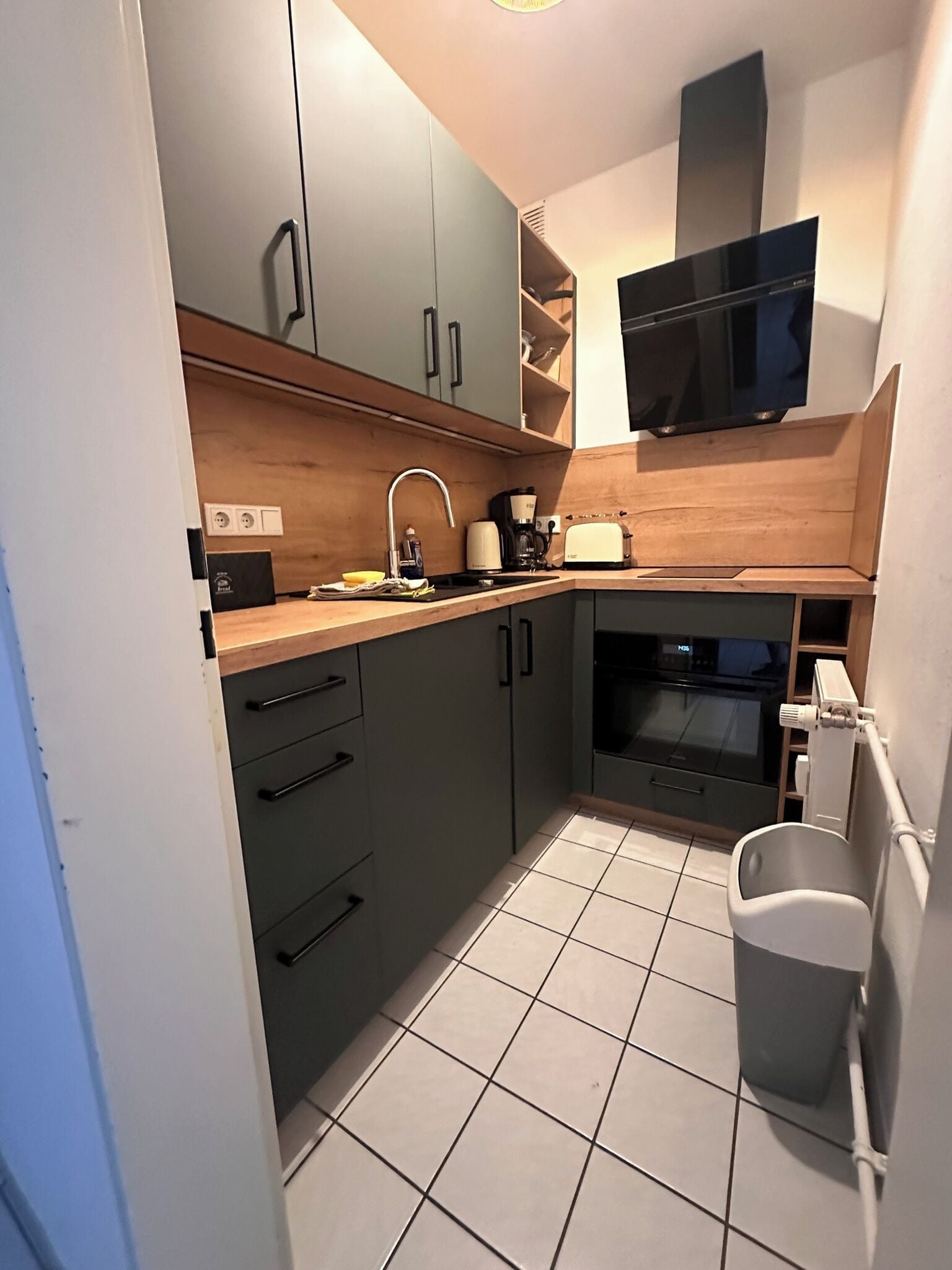 A compact kitchen with dark cabinets, a microwave, a toaster, and a sink.