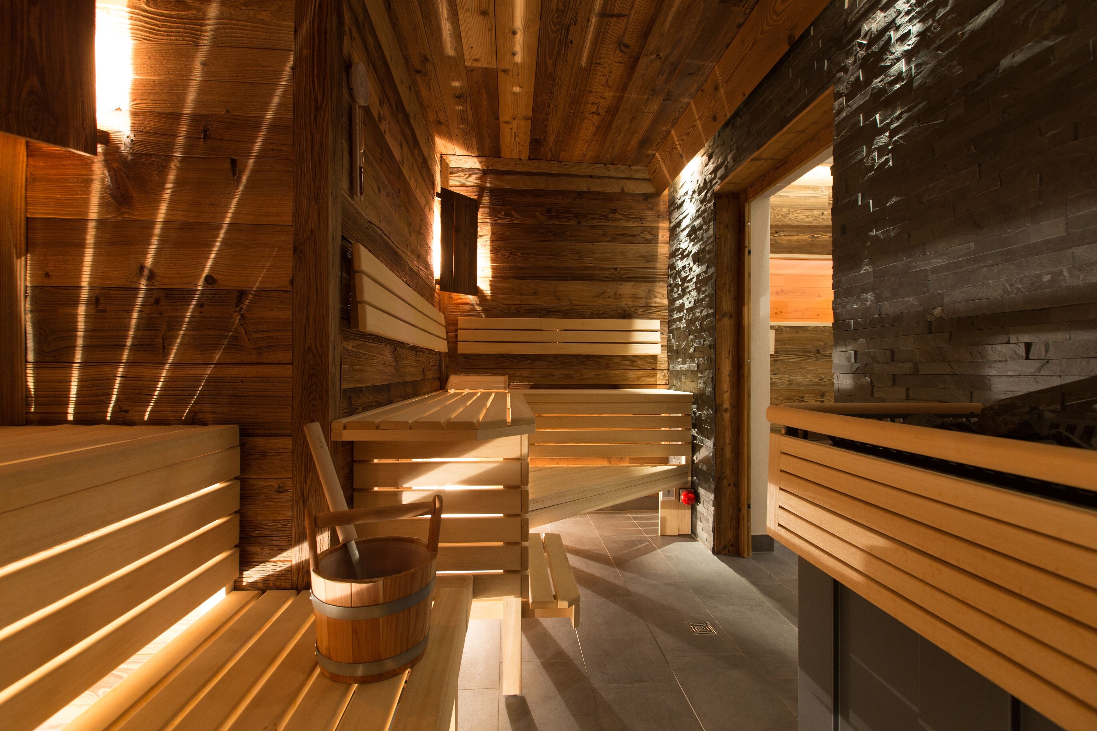Una sauna con bancos de madera y una pared de piedra.