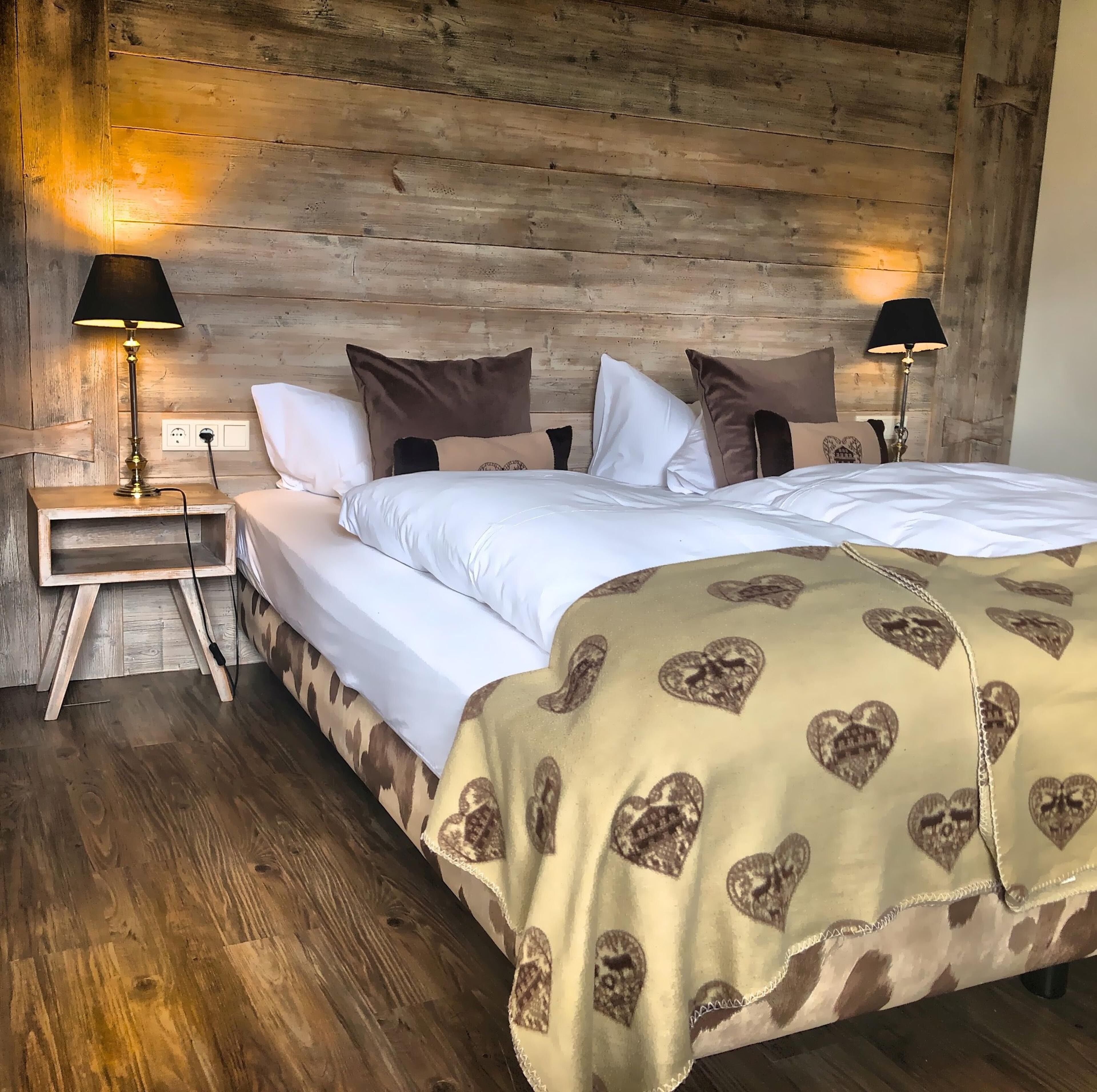 Un dormitorio con paneles de madera, una cama, dos lámparas de noche y una mesita de noche.