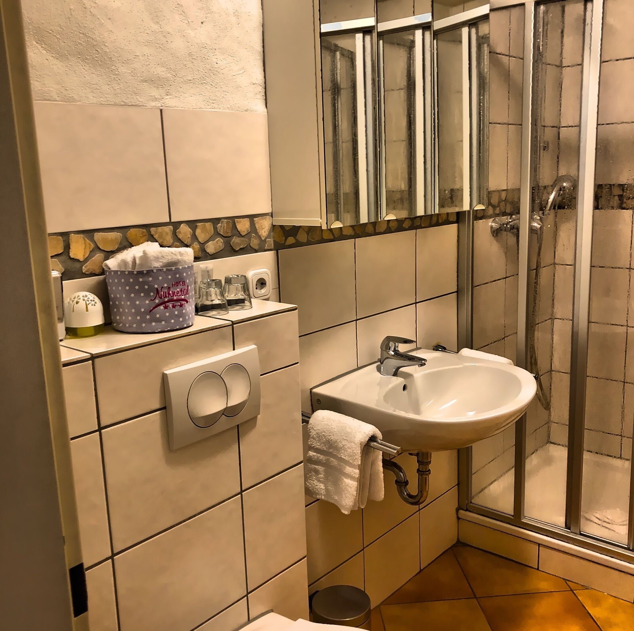 A bathroom with a white sink, a glass shower enclosure, and a towel rack.