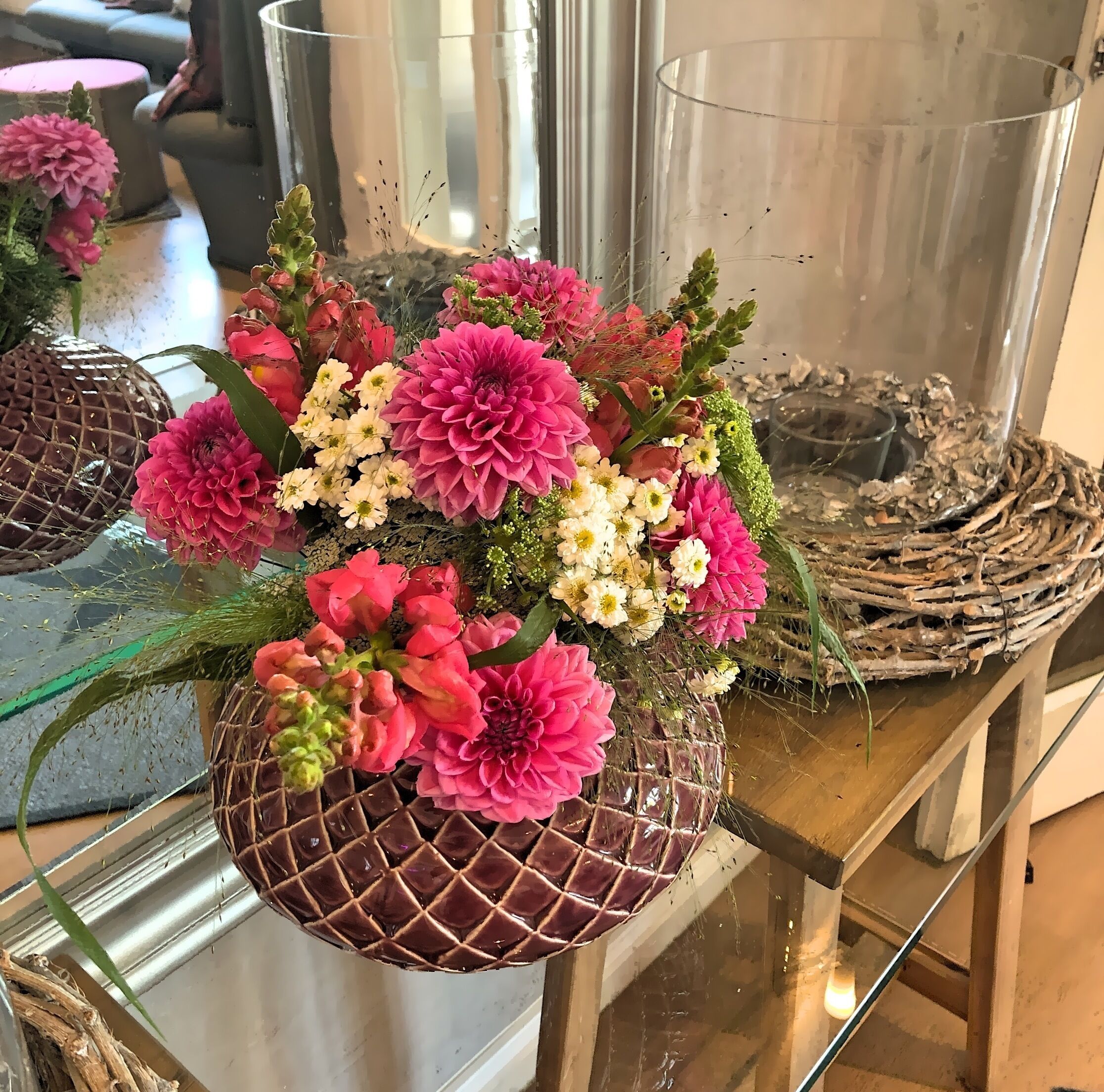 A floral arrangement in a decorative glass vase on a wooden table.