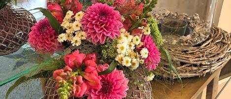 A floral arrangement in a decorative glass vase on a wooden table.
